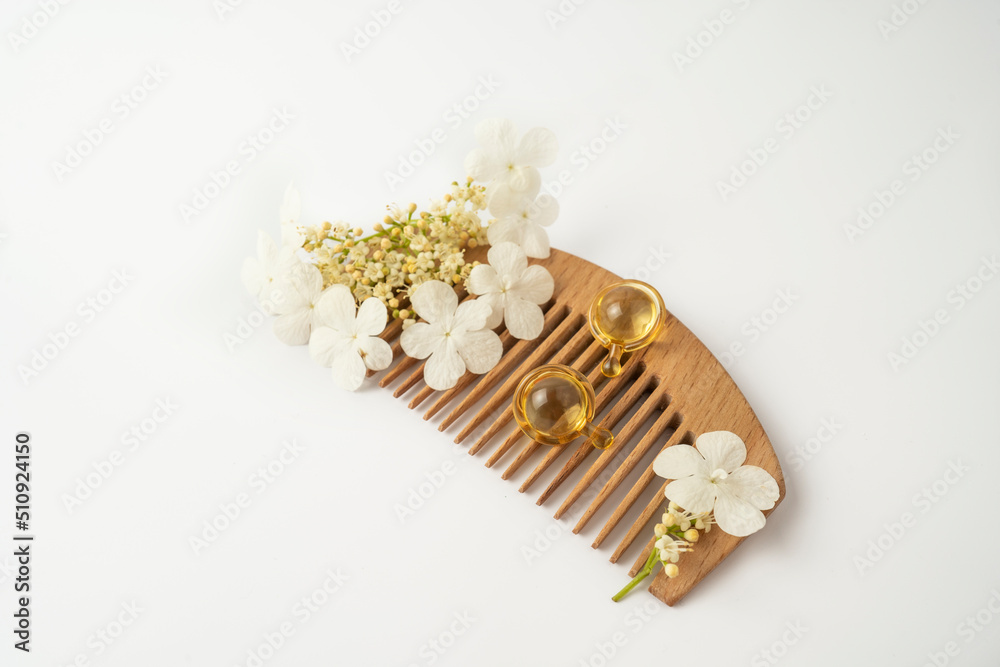 Natural oil vitamins golden capsules for hair lying on a wooden comb Natural oil vitamins golden capsules for hair lying on a wooden comb