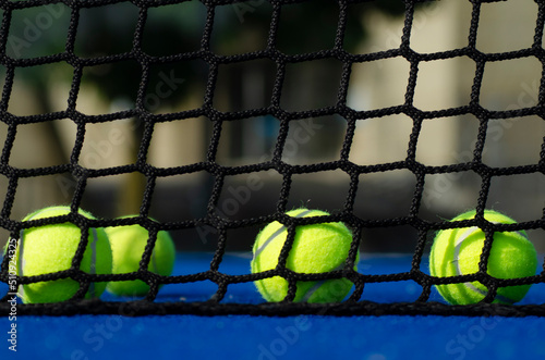 Selective focus, four balls behind the net on a blue padel tennis court