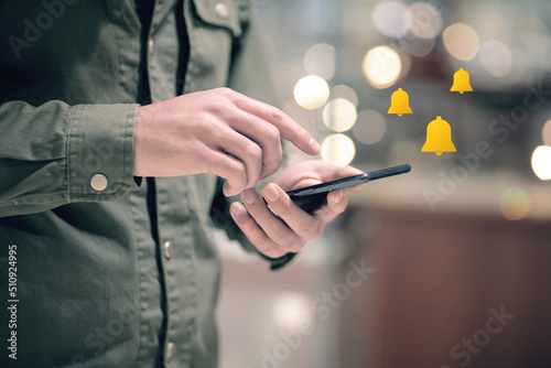 Golden notification bell. Man holding a phone in his hand