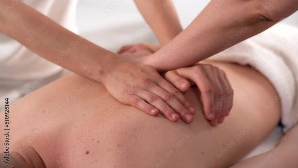 Two massage therapists do therapeutic massage, four-hand massage. caucasian man enjoys relaxing massage at spa treatments. Two massage therapists do therapeutic massage, four-hand massage. caucasian man enjoys relaxing massage at spa treatments.