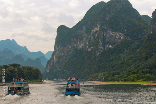 Set of boats sailing the li river in china with a landscape full of majestic chinese mountains in the background © Alex Wolf 