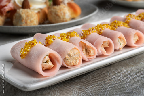 Stuffed ham rolls garnished with Dijon mustard. Plate on the festive table.
