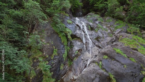 Aerial drone view of Fondra waterfall, the highest italian water jump. Flow of water trough rocks and trees in the forest in spring. Val Brembana, Bergamo, Italy. photo