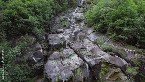 Aerial drone view of Fondra waterfall, the highest italian water jump. Flow of water trough rocks and trees in the forest in spring. Val Brembana, Bergamo, Italy. photo