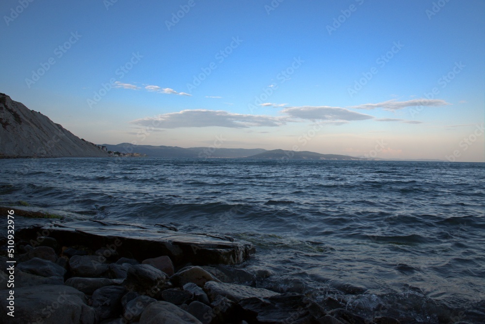 Obraz premium Coast of the Black Sea at sunset. Summer late evening. Beautiful seascape. Blue sky, steep cliffs, endless sea. Panoramic view. Russia.