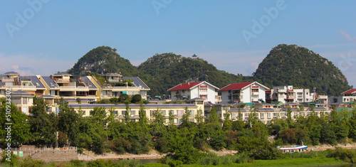 landscape photography of a village with chinese architecture houses near the li river in the guilin region of china with mountains in the background