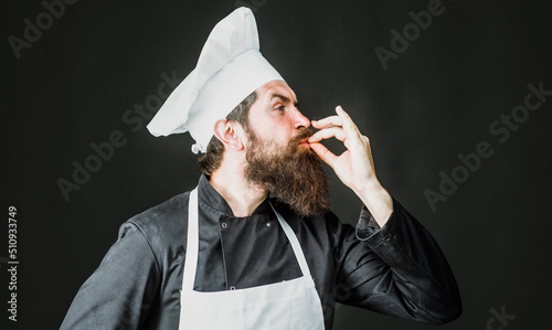 Professional chef shows sign for delicious. Male cook, baker in uniform with taste approval gesture.