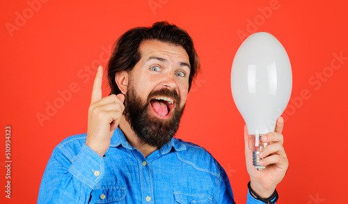 Good idea. Happy man with light bulb. Bearded male with lamp pointing finger up. Guy with lightbulb.