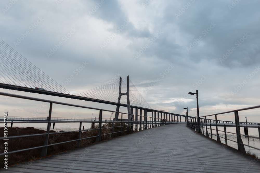 Wooden pier with the Vasco da Gama Bridge on a gray overcast day in Lisbon