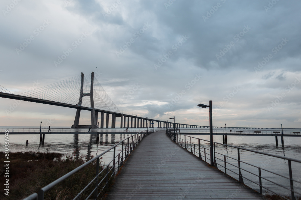 Beautiful view of the wooden pier, the long Vasque da Gama Bridge in cloudy weather. Journey to Lisbon, Portugal