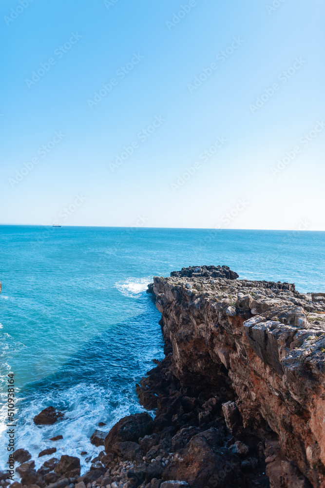 Amazing blue ocean with rock, waves and blue clear sky