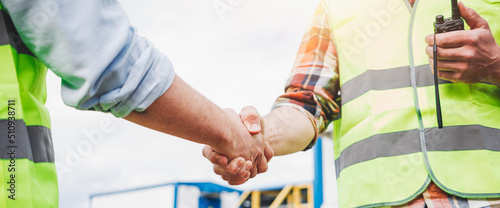Close up handshake of two engineers on produce site. Group of industries workers meet on manufacture site shake hands photo