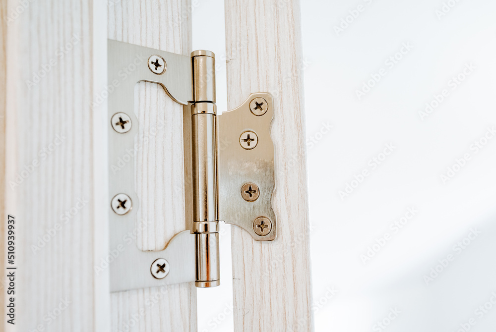 Obraz premium The hinge of the door is shot close-up, steel hinges are attached to the jamb of the doorway, cross-shaped screws are screwed into the door, interior details.