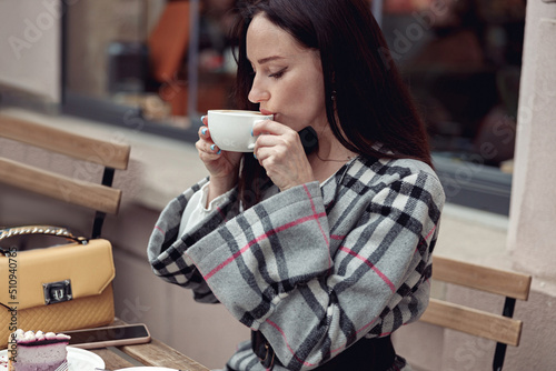 Photos Beautiful young brunette woman sipping cappuccino outside the coffee place