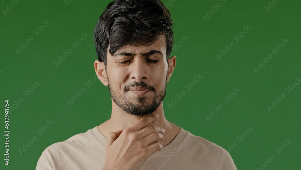 Indian sick young arab man touch neck suffer from angina has sore throat unhealthy guy painful swallow feel discomfort coronavirus disease symptom respiratory infection stand isolated in green studio Indian sick young arab man touch neck suffer from angina has sore throat unhealthy guy painful swallow feel discomfort coronavirus disease symptom respiratory infection stand isolated in green studio