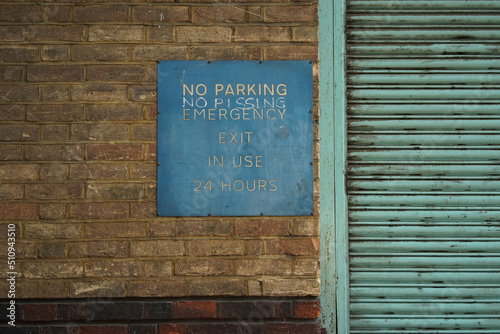 No Parking Sign on a Brick Wall with a Garage Door