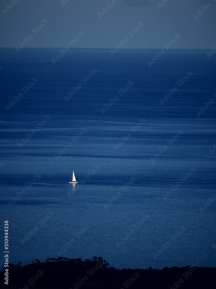 Sailboat in the sea, the coast is not too far.