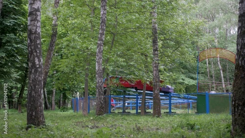 People riding on an old half-empty authentic soviet rollercoaster in local park. Friedns enjoy their free time in amusement park on a small wagon ride. Dated Eastern European theme park attraction 
