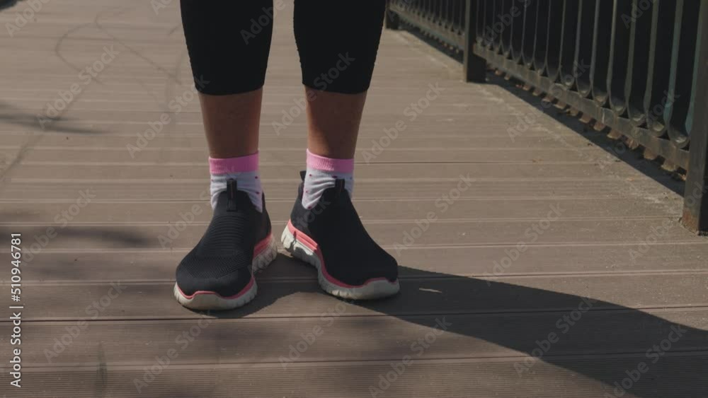 legs in black pink snickers warming up on wooden path in park, feet rotation exercises, close-up. concept of healthy lifestyle, sport outdoors, working out fresh air, steps nft finances, money concept legs in black pink snickers warming up on wooden path in park, feet rotation exercises, close-up. concept of healthy lifestyle, sport outdoors, working out fresh air, steps nft finances, money concept