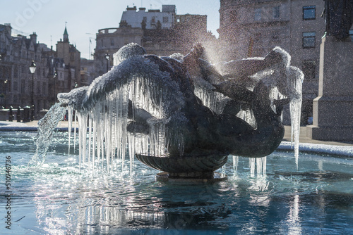 Frozen fountain statues of Trafalgar Square in London. Icicles mystically hanging off bronze water fountain photo