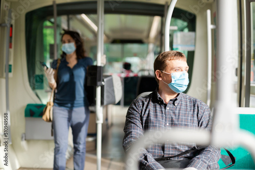 Foto Adult man wearing medical mask and rubber gloves riding city bus on way to work in sunny spring morning