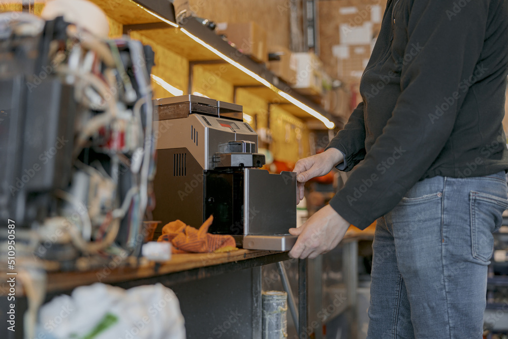 Professional worker inspecting detail of coffee machine in workshop Professional worker inspecting detail of coffee machine in workshop
