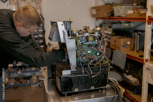 Male electrician repairing coffee machine in workshop