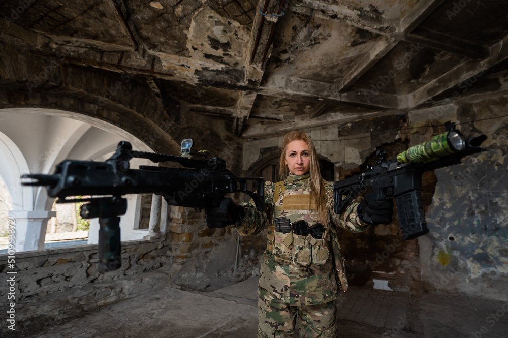 Fototapeta premium Caucasian woman in army uniform holding two machine guns. 