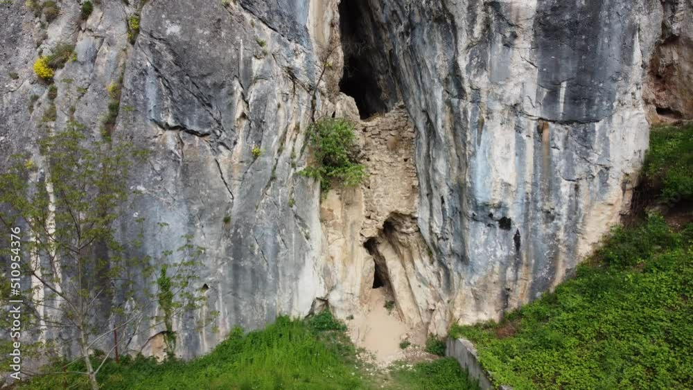 Aerial view of a large, mysterious cave in the rock, with some bushes on steep cliffs Aerial view of a large, mysterious cave in the rock, with some bushes on steep cliffs