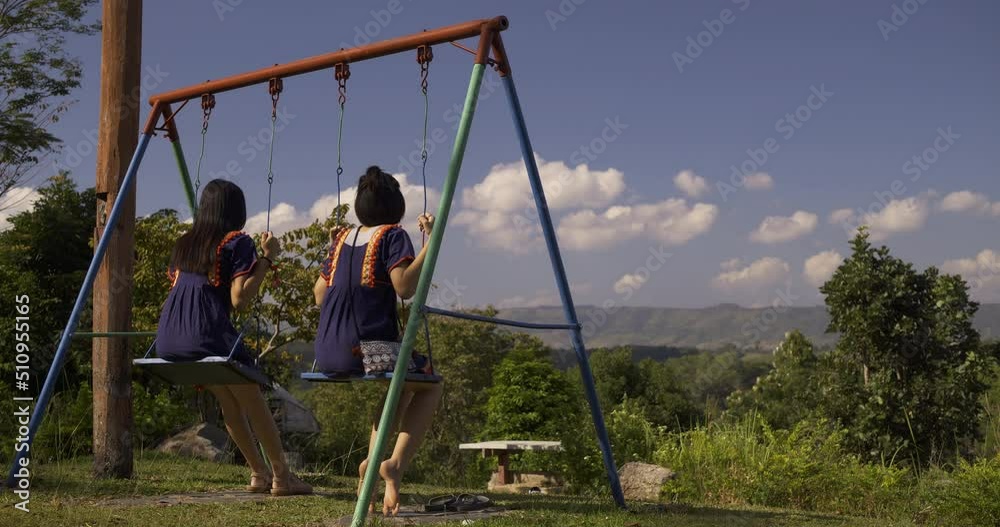Asian girl in Thai cultural dress relaxing on a swing.
Asian girl in Thai cultural dress relaxing on a swing.