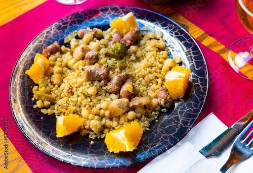 Traditional Spanish dish Migas tropezones from fried wheat flour with pieces of bacon, longaniza sausage, green peppers and orange.. photo