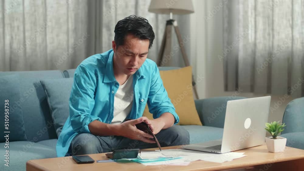Asian Man Checking Money On The Wallet Before Shaking His Head While Working With Laptop At Home
Asian Man Checking Money On The Wallet Before Shaking His Head While Working With Laptop At Home