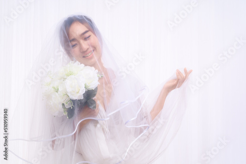 asian bride in white gown with veil holding flower bouquet