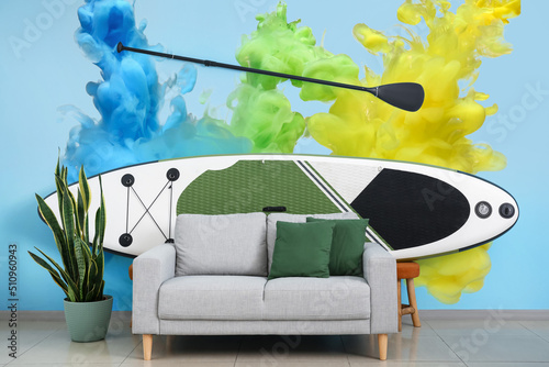 Canvas Print Interior of living room with sofa and board for sup surfing near wall with print