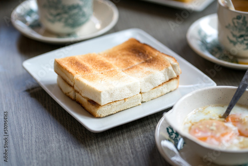 Oriental asian traditional Hainanese breakfast set with toast bread, half boiled eggs and coffee.