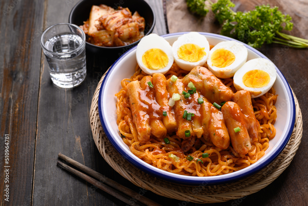 Korean spicy instant noodle with Tteokbokki, sausage and egg on wooden background