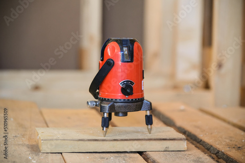 Red Laser level measuring tool for accuracy on wood floor. general contractor, building supplies, measurement. Construction of a frame wooden house. photo