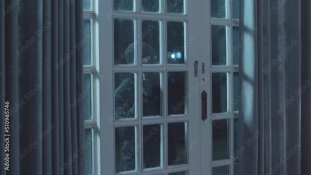 Thief Man Holding Flashlight Looking Inside The House While Standing Outside In The Dark Night
