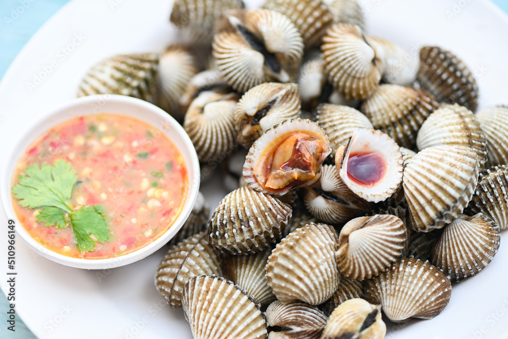 Cockles on white plate with seafood sauce on table background , Fresh raw shellfish blood cockle ocean gourmet seafood in the restaurant Cockles on white plate with seafood sauce on table background , Fresh raw shellfish blood cockle ocean gourmet seafood in the restaurant