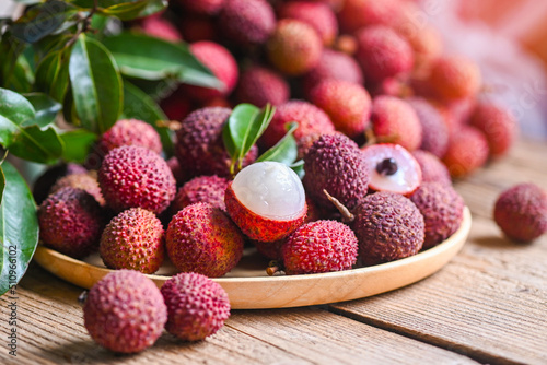 Lychee frui with green leaf on wooden plate background , fresh ripe lychee peeled from lychee tree at tropical fruit Thailand in summer