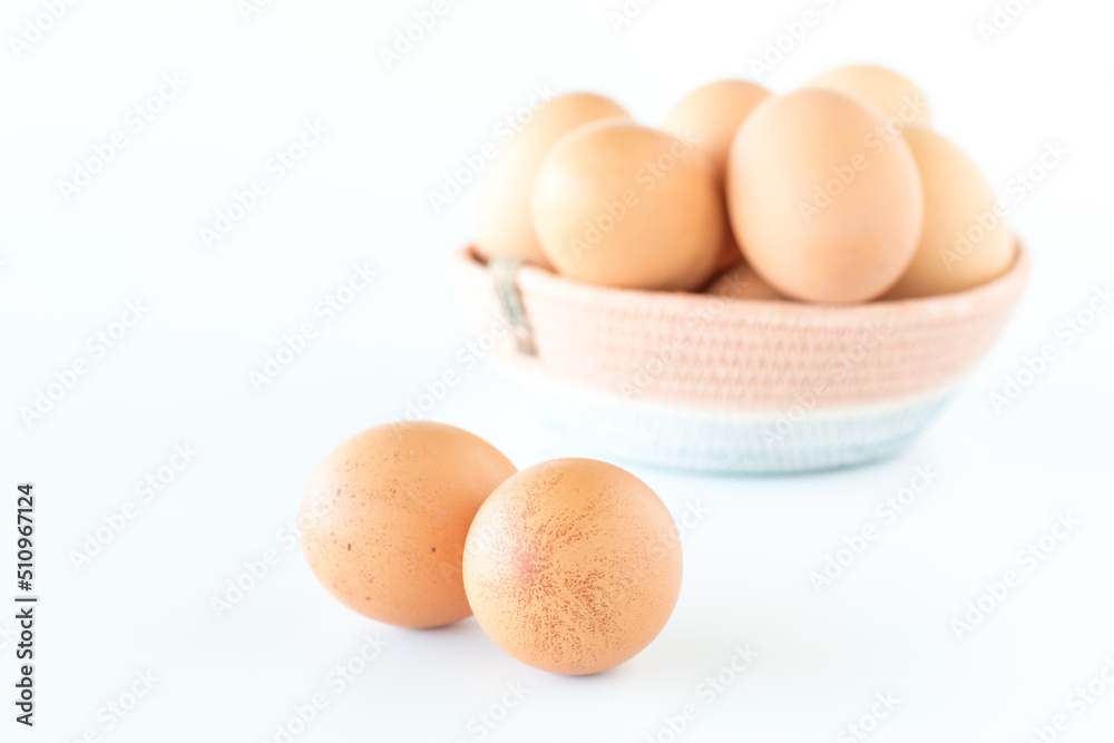 A basket of fresh free range brown eggs with two spotted eggs in front. A basket of fresh free range brown eggs with two spotted eggs in front.