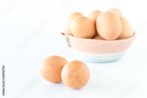 A basket of fresh free range brown eggs with two spotted eggs in front.