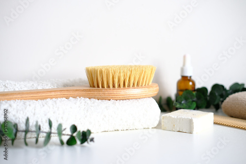 Massage wooden body brush on the background of spa items. Homemade body care. Dry lymphatic drainage massage and spa treatments.