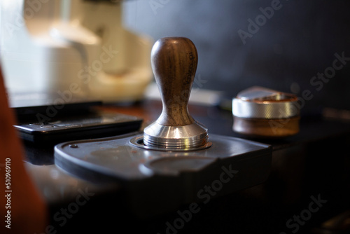 Ground coffee tamper on tamper plate. Barista's equipment