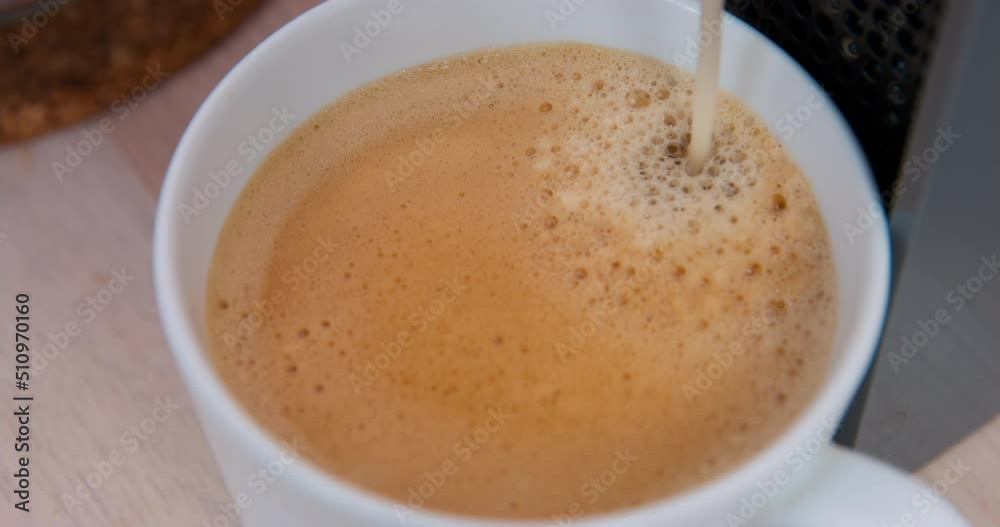 Fresh hot coffee is poured into the cup from an automatic coffee machine, forming a thick foam on the surface of drink, top view, close up. Hot beverage for breakfast or for dessert Fresh hot coffee is poured into the cup from an automatic coffee machine, forming a thick foam on the surface of drink, top view, close up. Hot beverage for breakfast or for dessert
