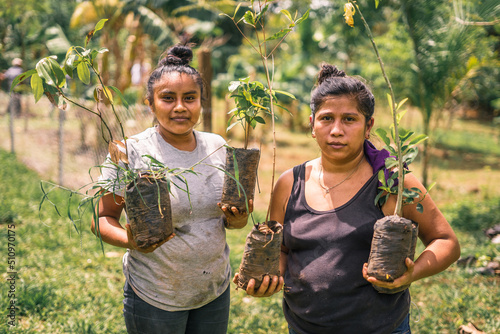 Nicaraguan women, mother and daughter holding plants in their hands and looking at camera in rural Masaya, Nicaragua photo