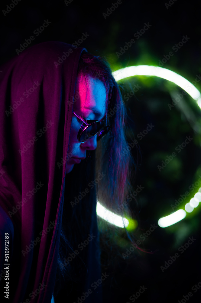 Portrait of asian man in hood and sunglasses in neon light. 