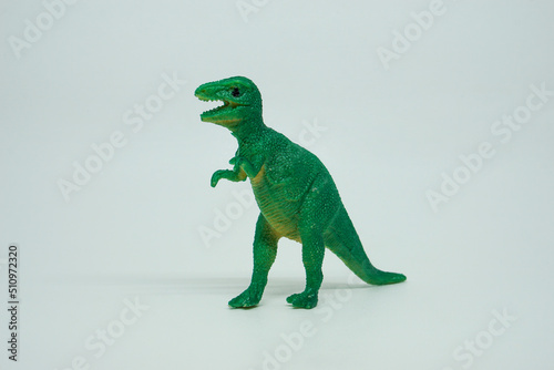 Side view of plastic green Tyrannosaurus rex dinosaur plastic toy for kids, isolated on a studio lighting background © LADALIDI