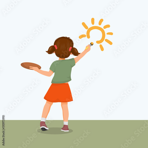 back view of cute little girl artist holding paintbrush and palette painting on the wall