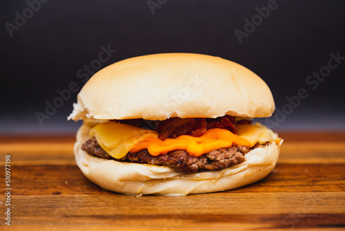 Delicious traditional Brazilian burger, X burger cheader, meat and cheese cheader. on wooden board.